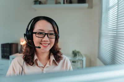 Asian woman smiling wearing headset providing cust 2026 01 11 10 34 47 utc - Forskjellen på enkeltpersonforetak (ENK) og aksjeselskap (AS)