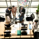 Multicultural business team standing around a desk 2026 03 05 11 48 53 utc - Outsourcing vs in-house: Økonomisk sammenligning for møtebookin...