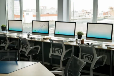 Row of computer monitors standing on desks against 2026 01 08 08 25 35 utc - Hvordan regne ut ROI for outsourcing: mal og eksempler (TCO, pa...