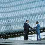 Shaking hands in corporate glass building 2026 01 08 00 31 14 utc - Teknologivalg for tverrbedrifts-samarbeid: skybasert ERP og integrasjons...