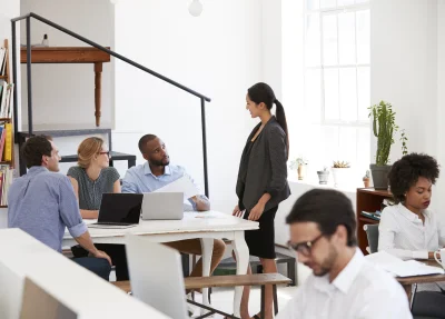 Woman talking with colleagues at a desk in open pl 2026 01 05 06 29 37 utc - Hvordan starte et AS, steg‑for‑steg (inkl. sjekkliste og tidsli...